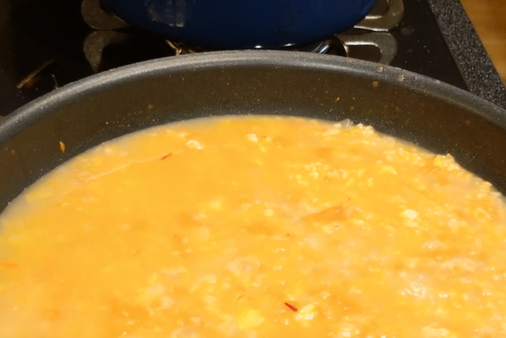 パエリアに魚介スープを入れる写真